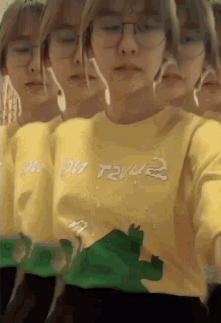 a woman wearing glasses and a yellow sweater with a green crocodile on it .