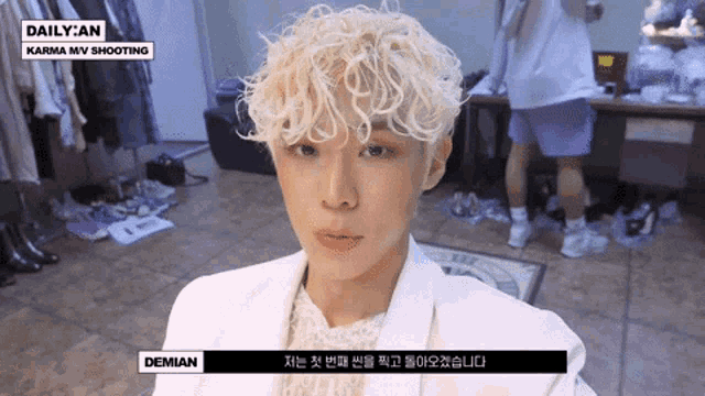 a man with blonde curly hair is wearing a white jacket that says daily an on it