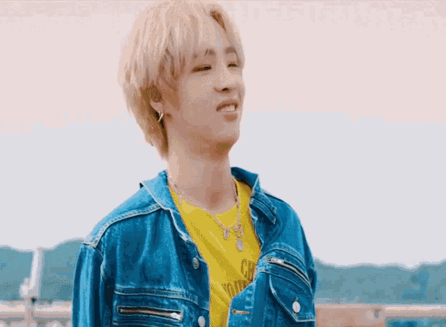a young man wearing a denim jacket and a yellow t-shirt that says california