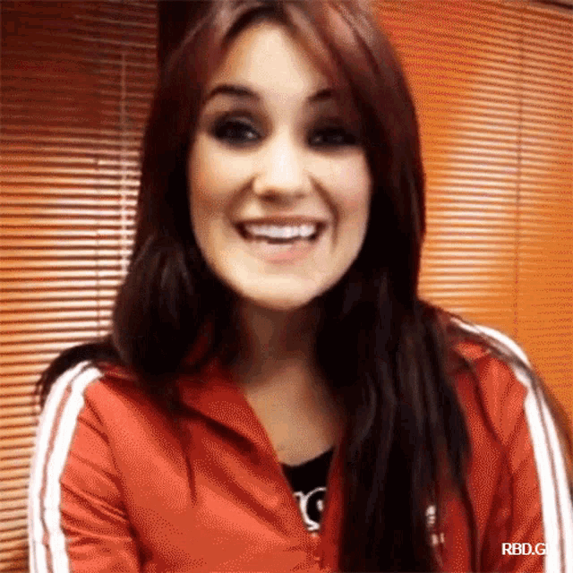 a woman wearing a red jacket with white stripes smiles