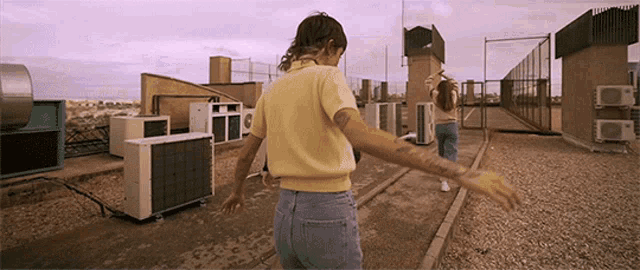 a woman with a tattoo on her arm is walking on a rooftop