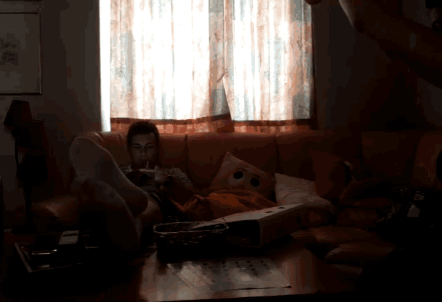 a person sitting on a couch with their feet up and a box on the floor