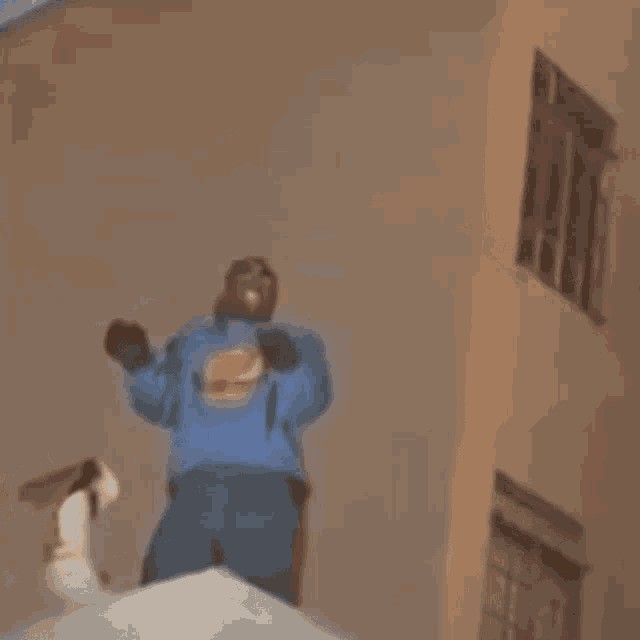 a man in a blue sweatshirt is standing in front of a building .
