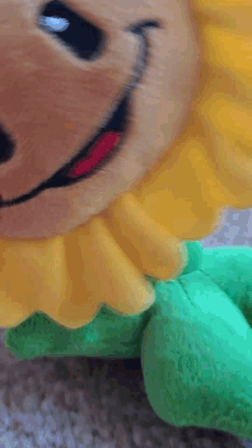 a stuffed animal with a yellow flower and green leaves is smiling