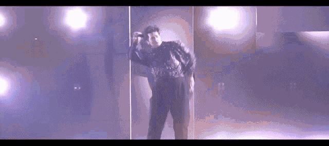 a man in a purple jacket is standing in front of a pole in a dark room .