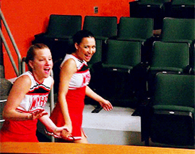 two cheerleaders wearing red and white uniforms with the word cheerleader on them
