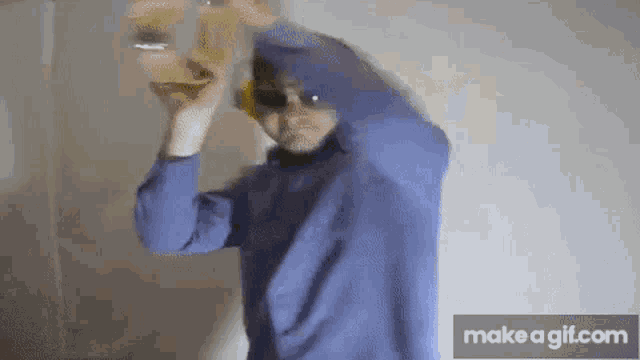 a man in a blue shirt and sunglasses is holding a tambourine in his hands .
