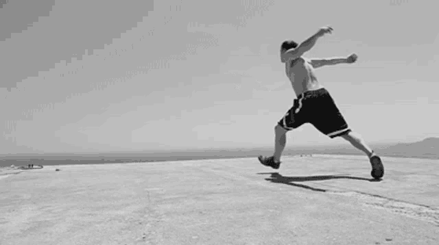 a man without a shirt is jumping in the air in a black and white photo