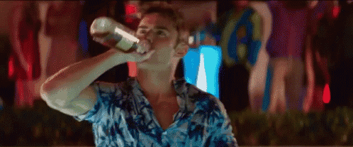 a man in a hawaiian shirt is drinking from a bottle at a party .