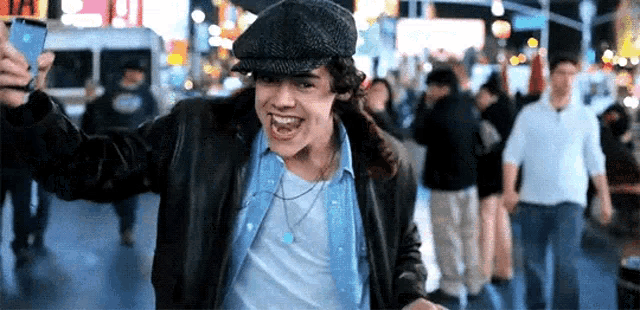 a man wearing a hat is taking a selfie in a crowded street .