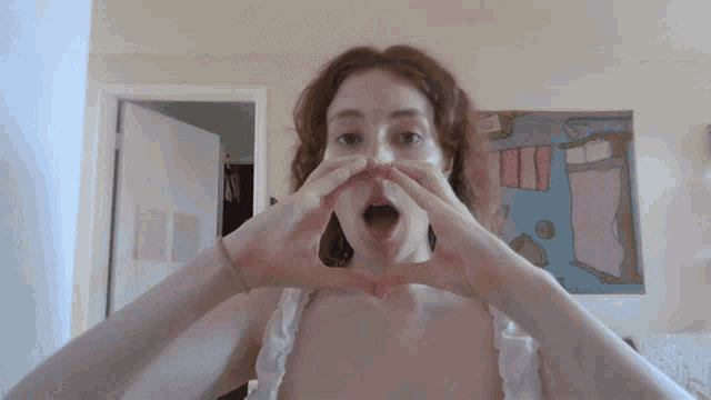 a woman makes a heart shape with her hands