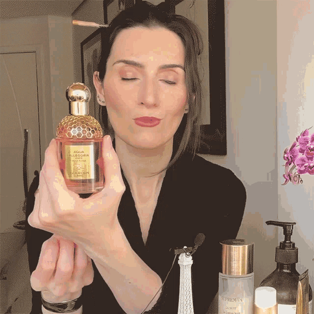 a woman holds a bottle of aqua allegoria perfume