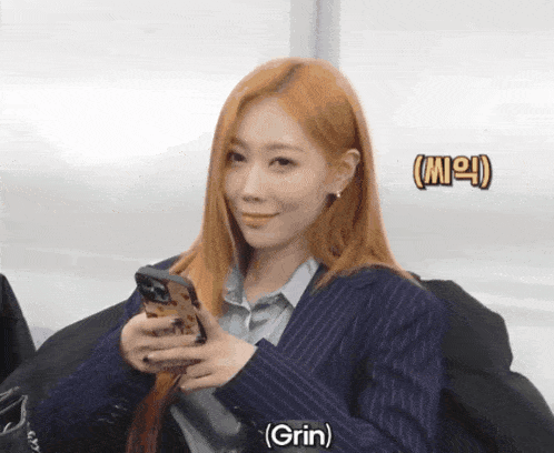 a woman in a suit is holding a cell phone and grin is written on the bottom