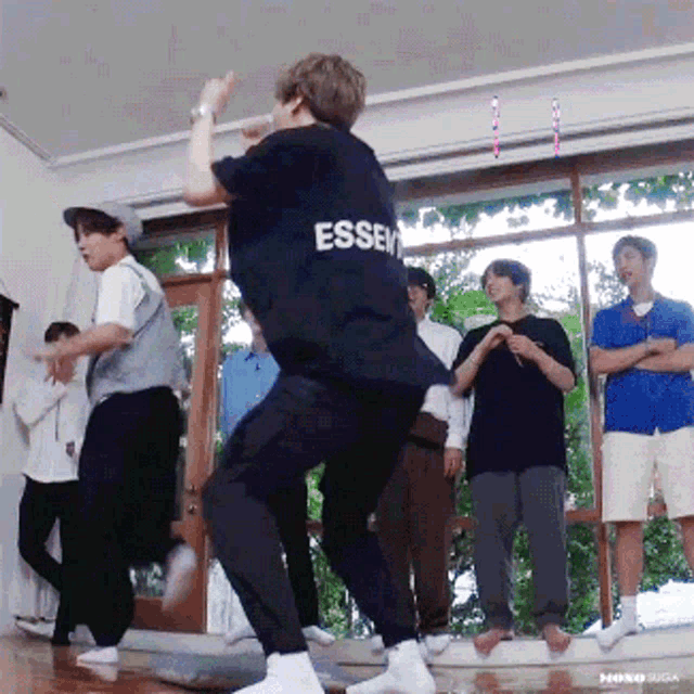 a man wearing a black shirt with the word essen on the back is dancing in front of a group of people