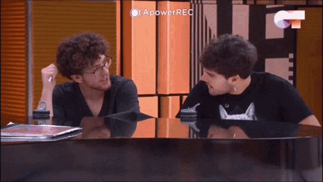 two men sitting at a table with a power rec logo on the bottom