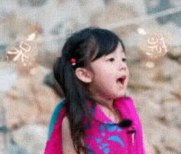 a little girl in a pink dress is standing on a beach .