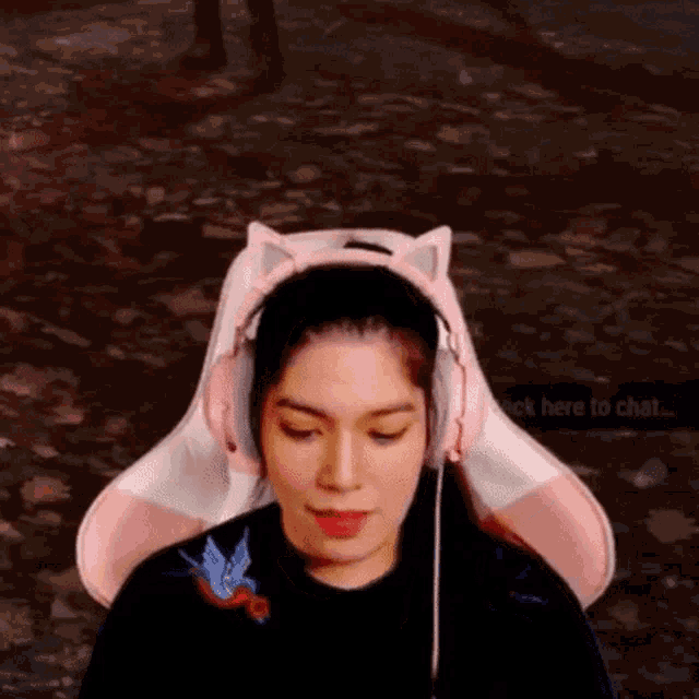 a woman wearing pink headphones and a cat ear headband says click here to chat