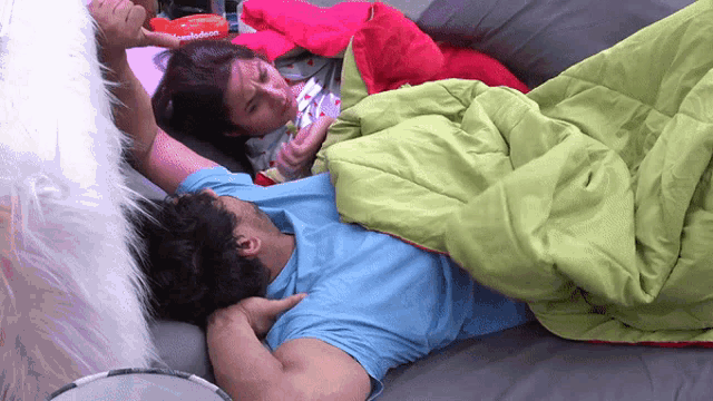 a man and a woman laying on a bed with a blanket that says nickelodeon