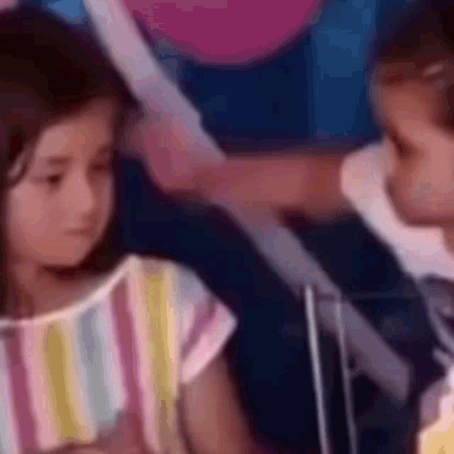 a little girl in a striped shirt is sitting next to a man in a suit .