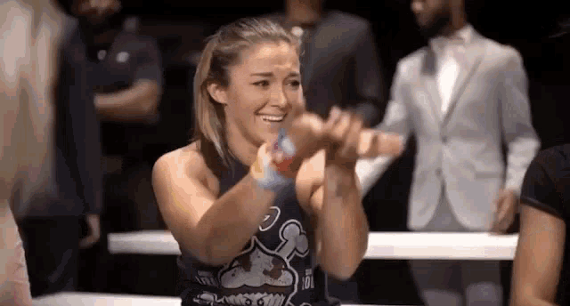 a woman is clapping her hands in a boxing ring while sitting at a table .