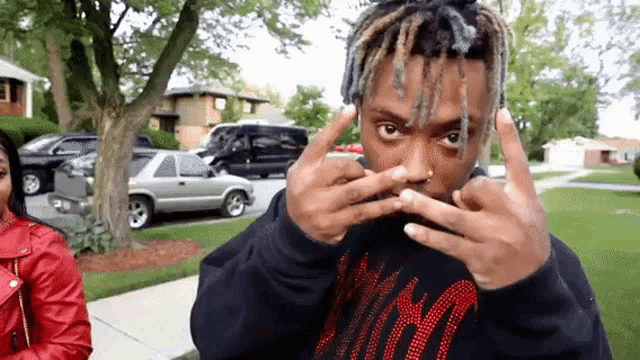a man with dreadlocks is making a funny face with his hands in front of his face .