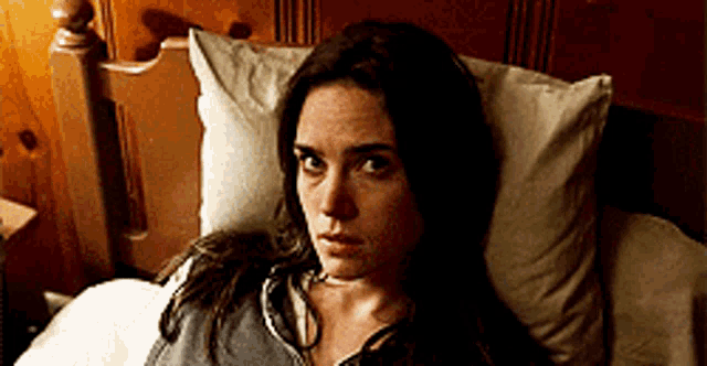 a woman is laying in a bed with a pillow on her head