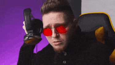 a man wearing red sunglasses and headphones is sitting in a yellow chair .