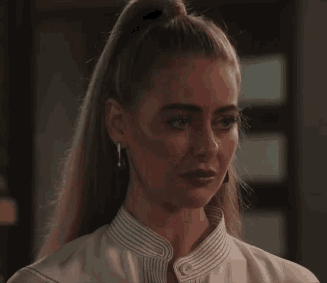 a woman with a ponytail and earrings looks sad