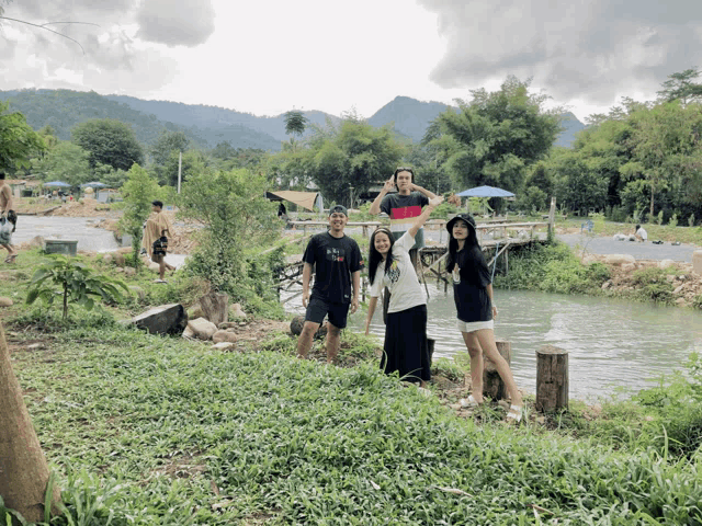 a group of people posing for a picture in front of a pond