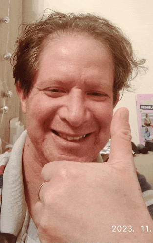 a man is smiling and giving a thumbs up in front of a book that says ' zemuru ' on it