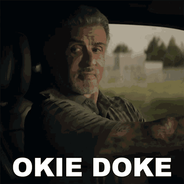 a man is driving a car with the words okie doke behind him