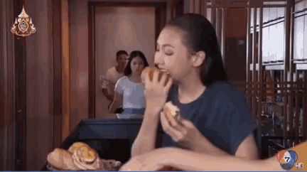 a woman is eating a sandwich in front of a sign that says ?