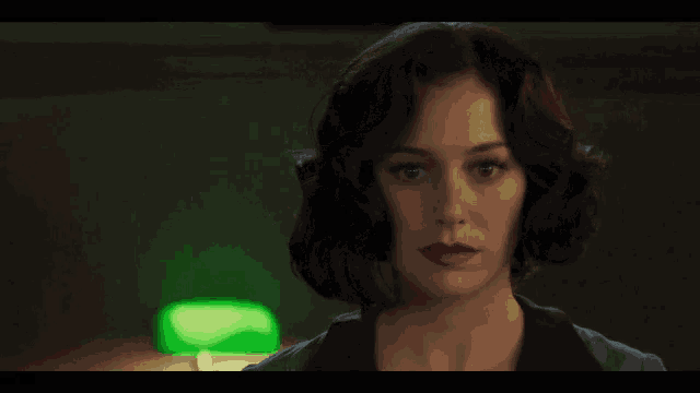 a close up of a woman 's face with a green lamp behind her