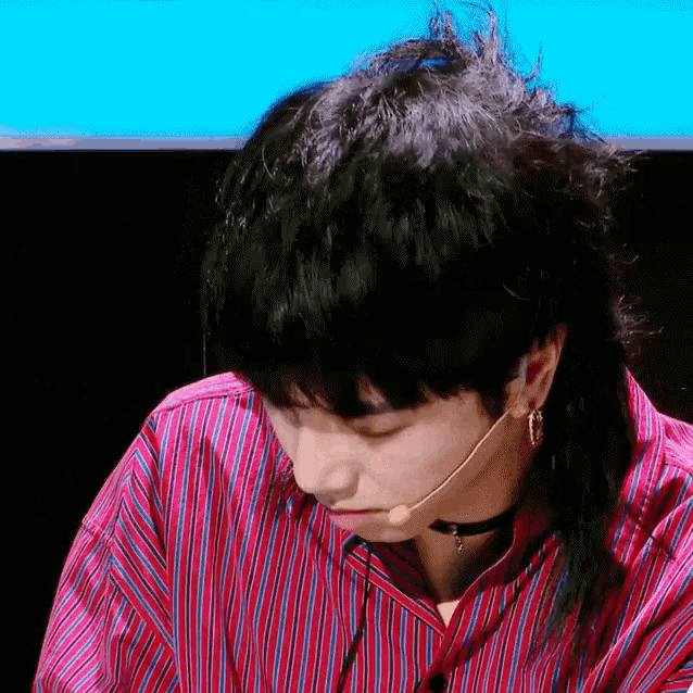 a close up of a person wearing a microphone and a striped shirt .
