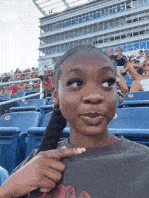 a girl sitting in a stadium pointing at a flamingo