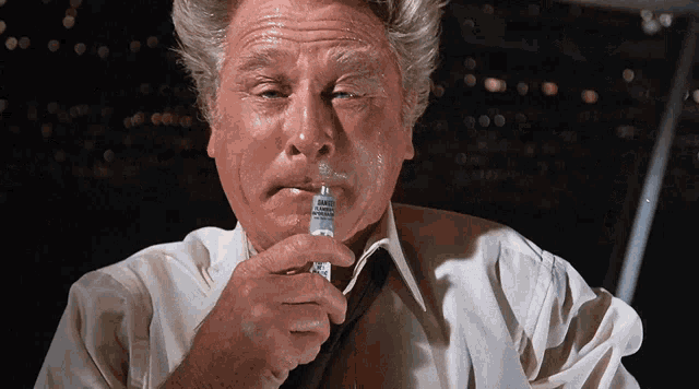 a man in a white shirt is smoking a cigarette with a label that says warning