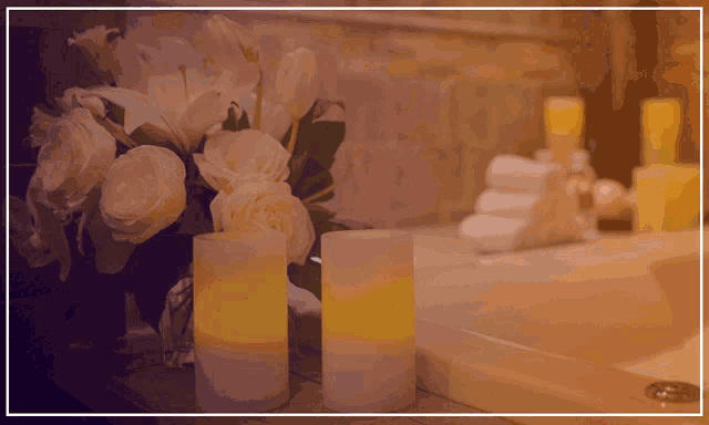 a bathroom with a vase of white flowers and two candles