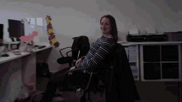 a woman in a striped shirt is sitting in a chair
