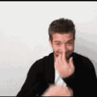 a man in a black jacket is making a funny face while covering his nose with his hand .