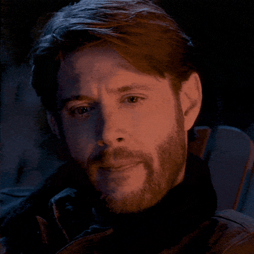 a close up of a man 's face with a beard in a dark room