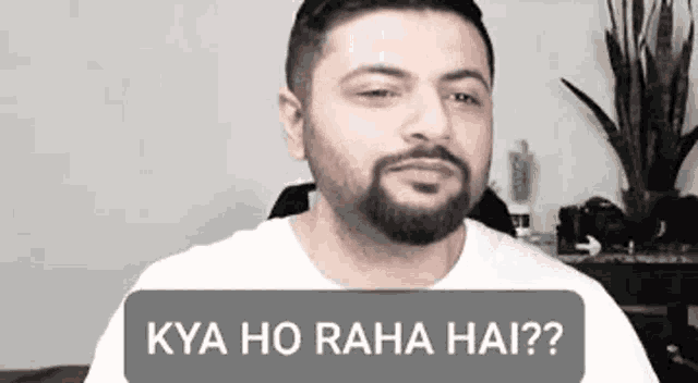 a man with a beard is wearing a white shirt and talking to someone .