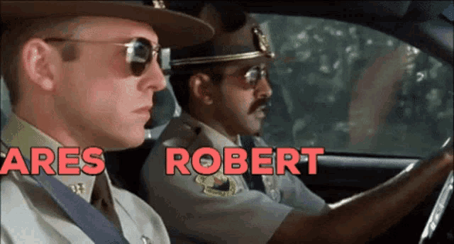 two police officers are driving a car and are named ares and robert respectively