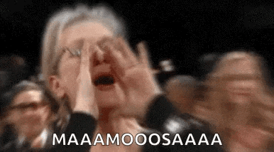 a woman is screaming in a crowd of people while holding her hands to her face .