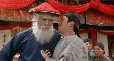 a man with a beard is hugging another man in a room .