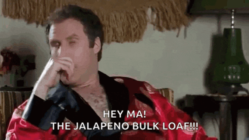 a man in a red robe is sitting in a chair and covering his mouth with his hand while talking on a cell phone .