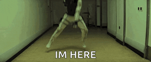 a person is jumping in the air in a hallway with the words im here written on the floor .