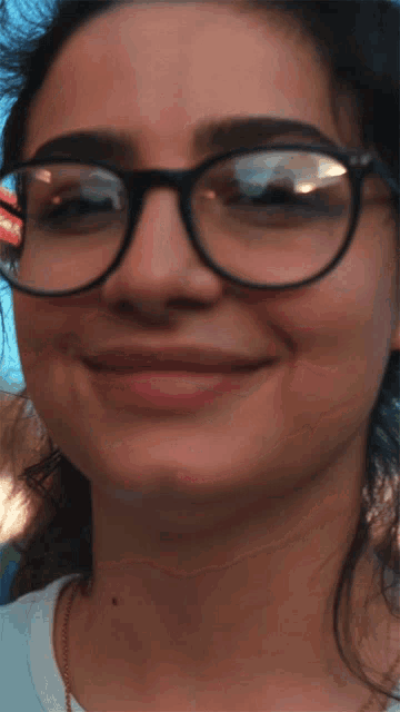a close up of a woman wearing glasses with a smile on her face