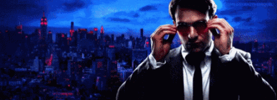 a man in a suit and tie is adjusting his glasses in front of a city skyline