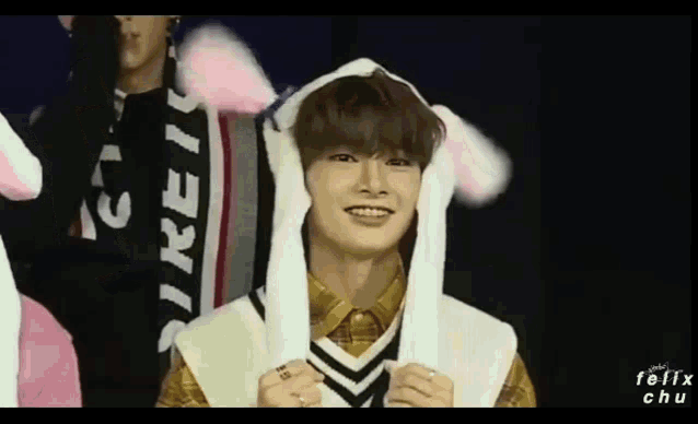 a young man wearing bunny ears is smiling while standing next to another person .