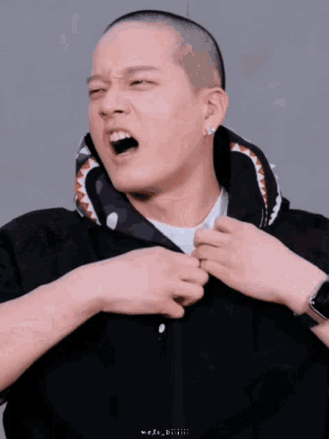 a man with a shaved head is wearing a black jacket with a shark print